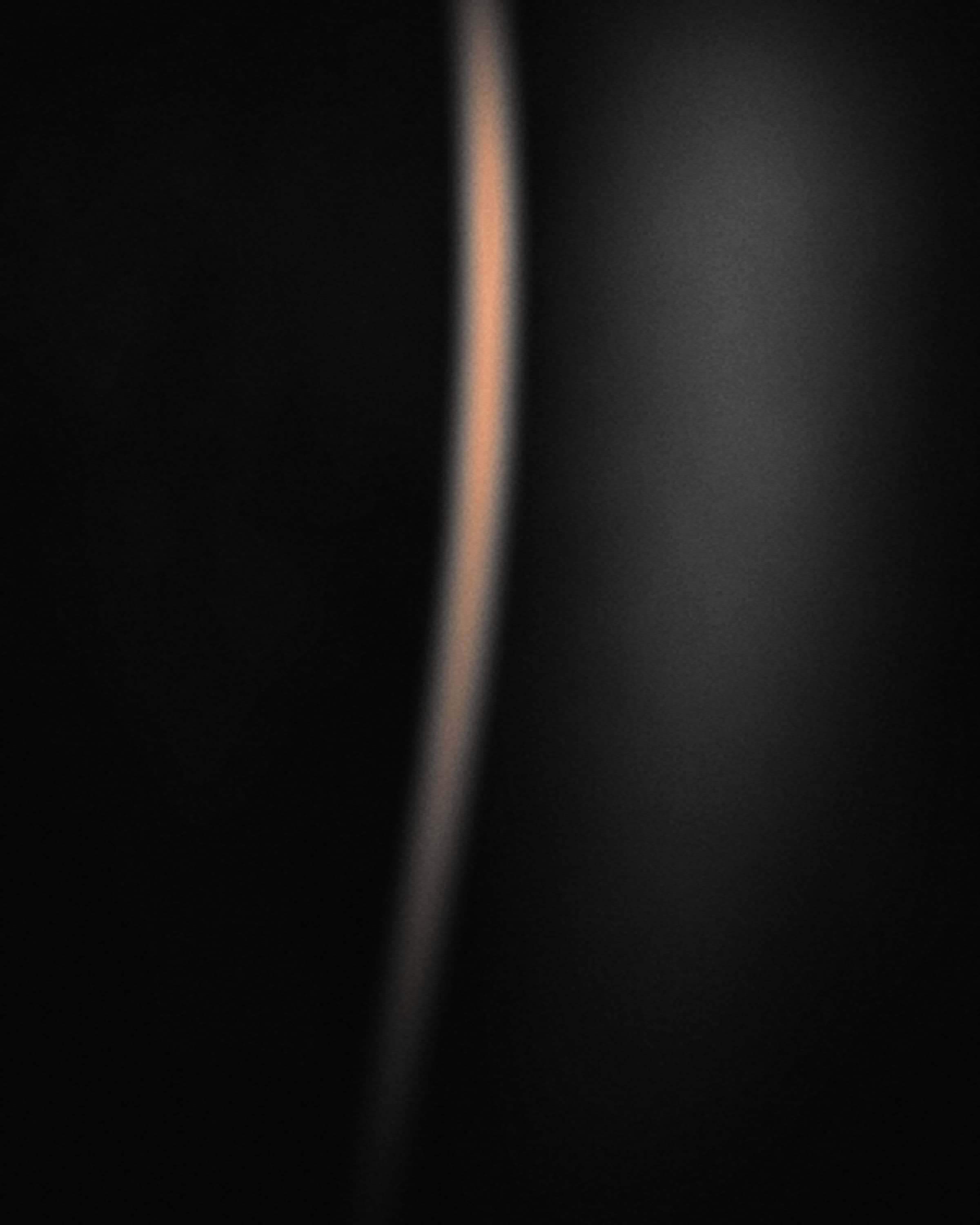Placeholder press photo 01 — vertical crop, a rim of light against deep black.